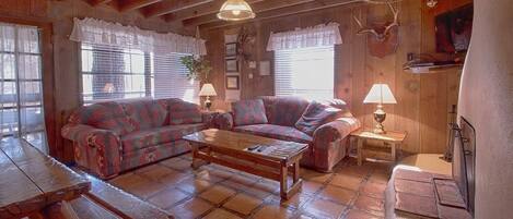 A cozy living room with a sofa set, a wooden coffee table, and a fireplace.