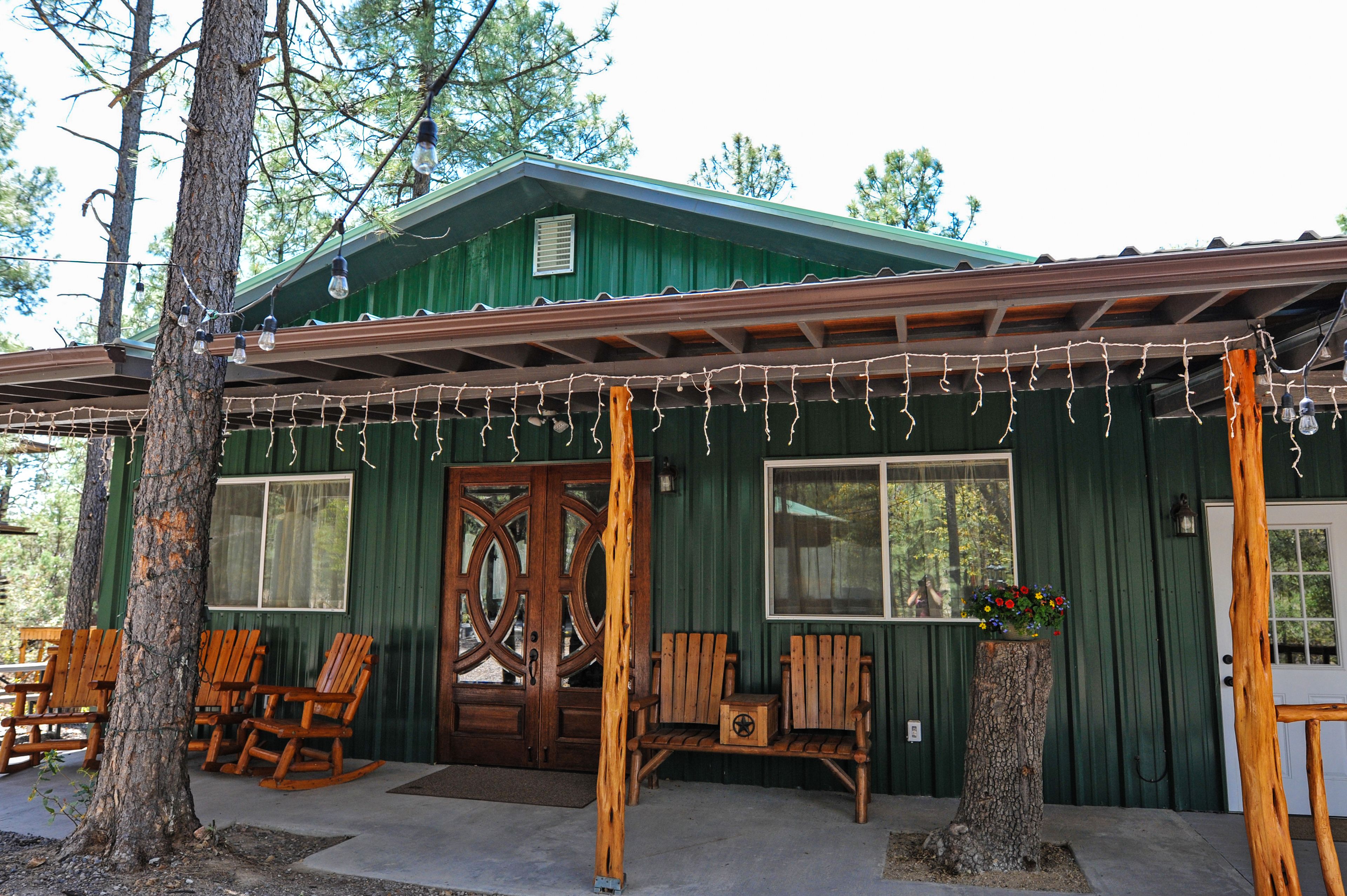 Une cabane rustique dotée d’une véranda, de chaises berçantes en bois et d’une grande porte en bois.