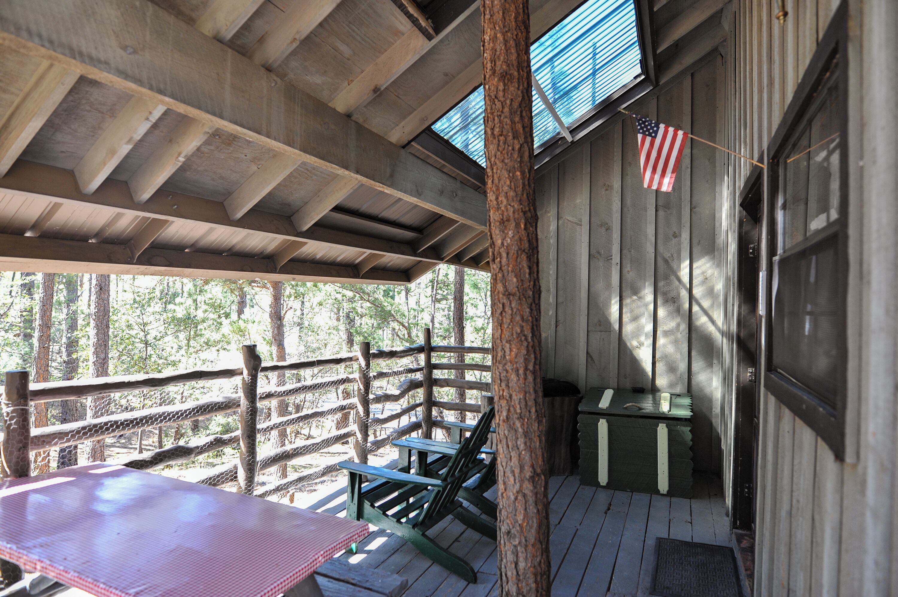 A wooden deck with a table and chairs, a rope fence, and an American flag.