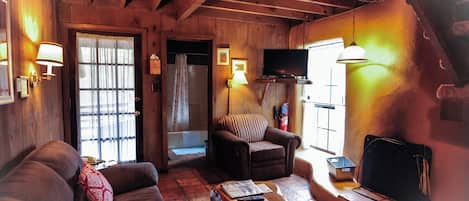 A cozy wooden interior with a sofa, armchair, and a television.