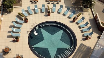 A rooftop pool area with a star-shaped design, surrounded by lounge chairs and potted plants.