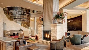 A spacious living area with a fireplace, comfortable seating, and a staircase leading to an upper level. - Archer Hotel Austin at the Domain (Austin)