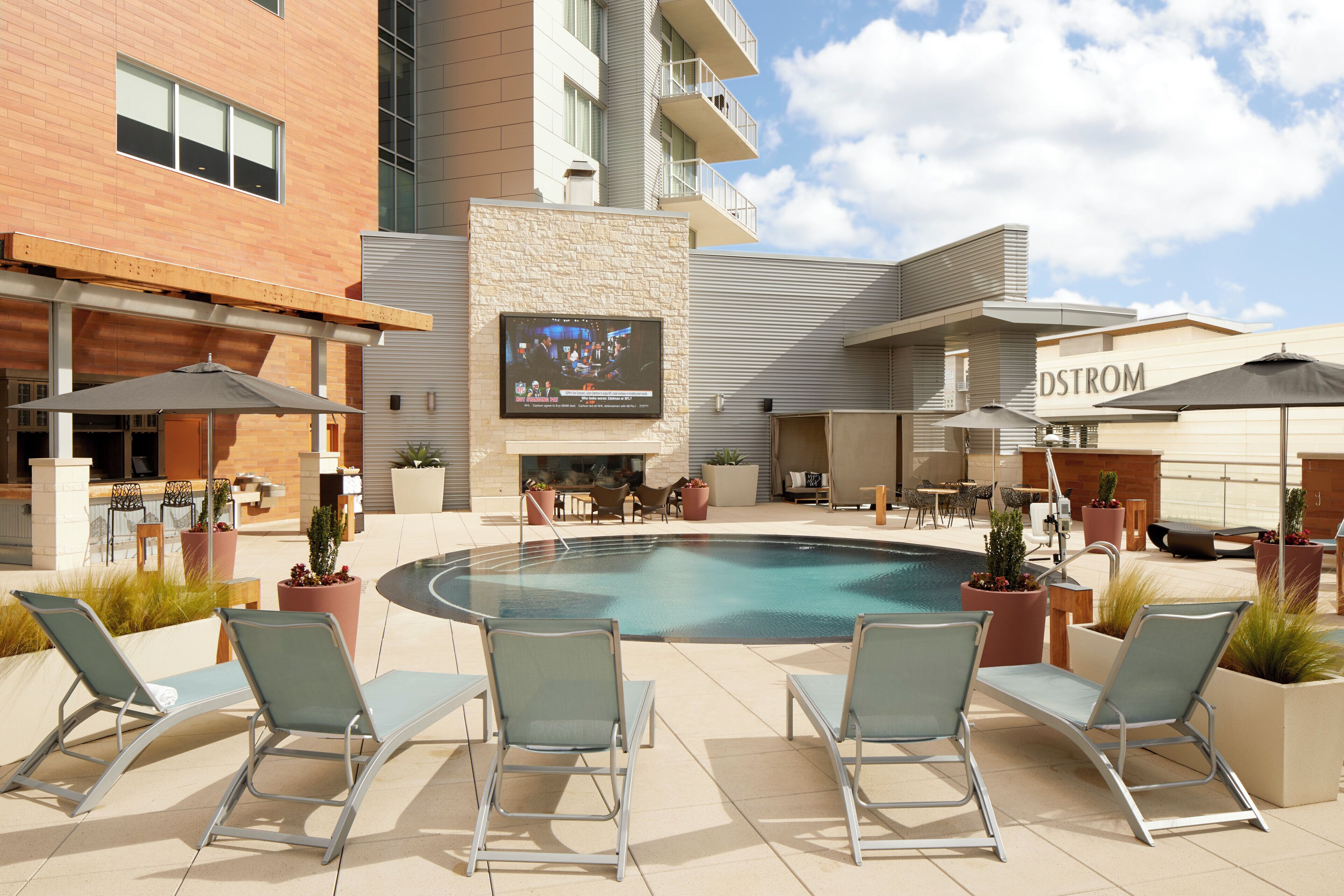 A poolside area with lounge chairs, a flat-screen TV, and outdoor seating.