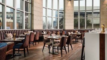 A restaurant with high ceilings, large windows, and a mix of booth and table seating.