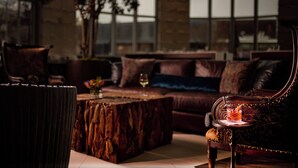 A cozy lounge area with a leather sofa, a wooden coffee table, and a glass of wine. - Archer Hotel Austin at the Domain (Austin)