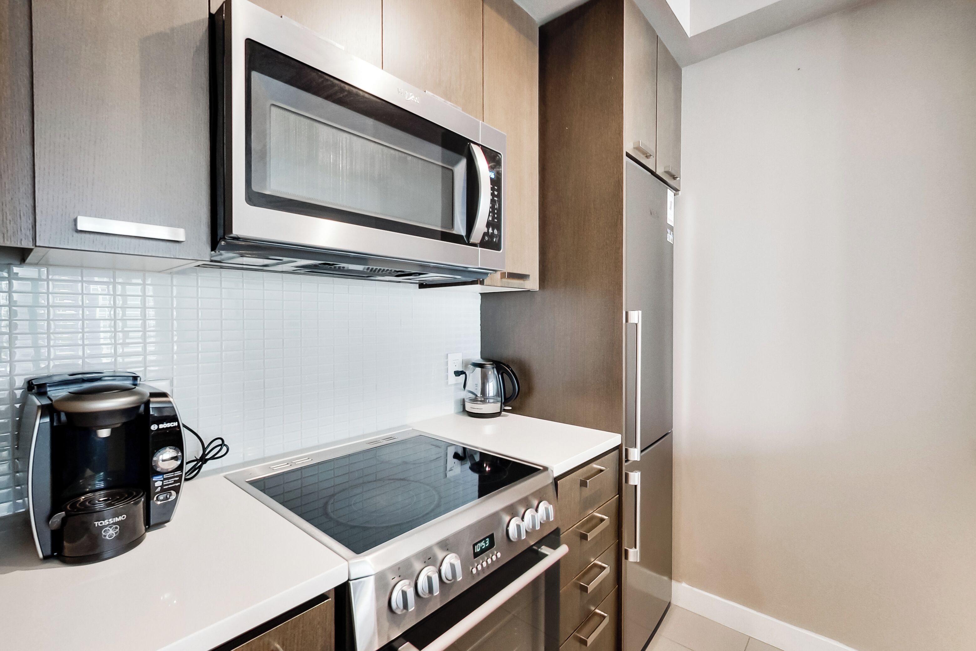 Una cocina moderna con microondas integrado, hervidor eléctrico y cafetera.