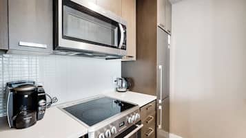 Una cocina moderna con microondas integrado, hervidor eléctrico y cafetera.