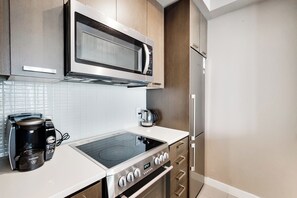 A modern kitchen with a built-in microwave, electric kettle, and a coffee maker. - Spectacular Views Apartments (Toronto)