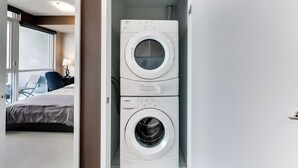 A hotel room with a bed, a desk, and a washing machine. - Spectacular Views Apartments (Toronto)