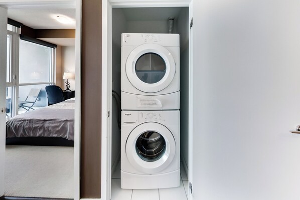 A hotel room with a bed, a desk, and a washing machine. - Spectacular Views Apartments (Toronto)