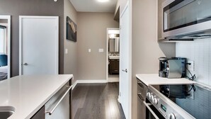A compact kitchen with a microwave, coffee maker, and a stove. - Spectacular Views Apartments (Toronto)