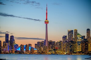 A city skyline with a prominent tower and various high-rise buildings. - Spectacular Views Apartments (Toronto)
