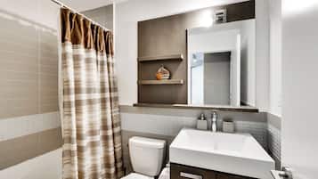 Un baño moderno con cortina de ducha, inodoro, lavabo y espejo.