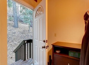 A wooden door with a small window, a wooden bench, and a shelf with a plate and a sign.