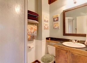 A bathroom with a toilet, sink, and a towel rack with folded towels.