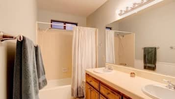 A bathroom with two sinks, a large mirror, and a shower area.