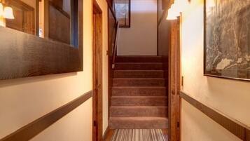 A narrow hallway with a carpeted staircase, wooden walls, and a framed picture on the right.