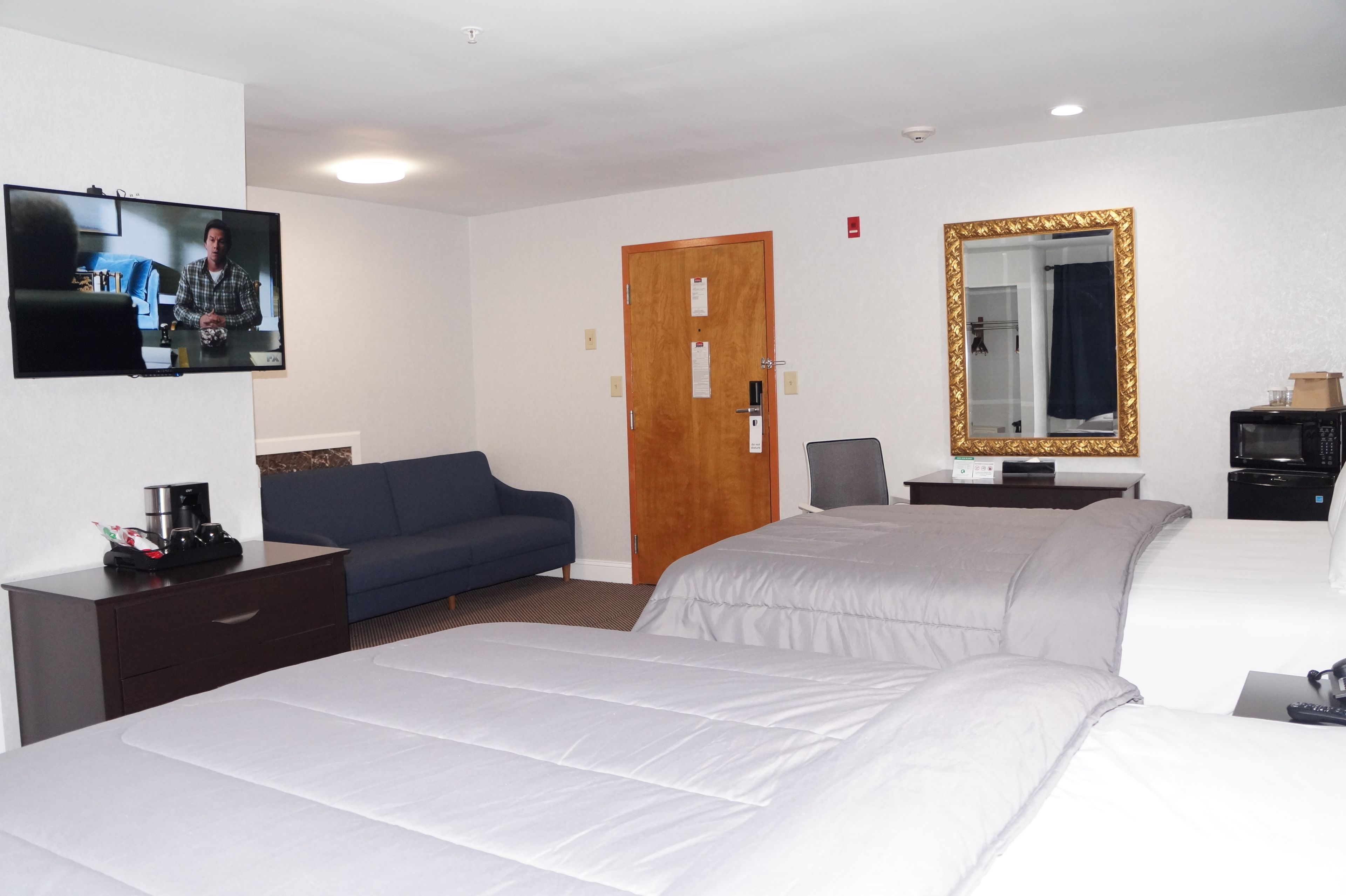Habitación de hotel con cama, televisión, escritorio, silla y espejo.