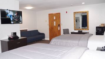 Habitación de hotel con cama, televisión, escritorio, silla y espejo.