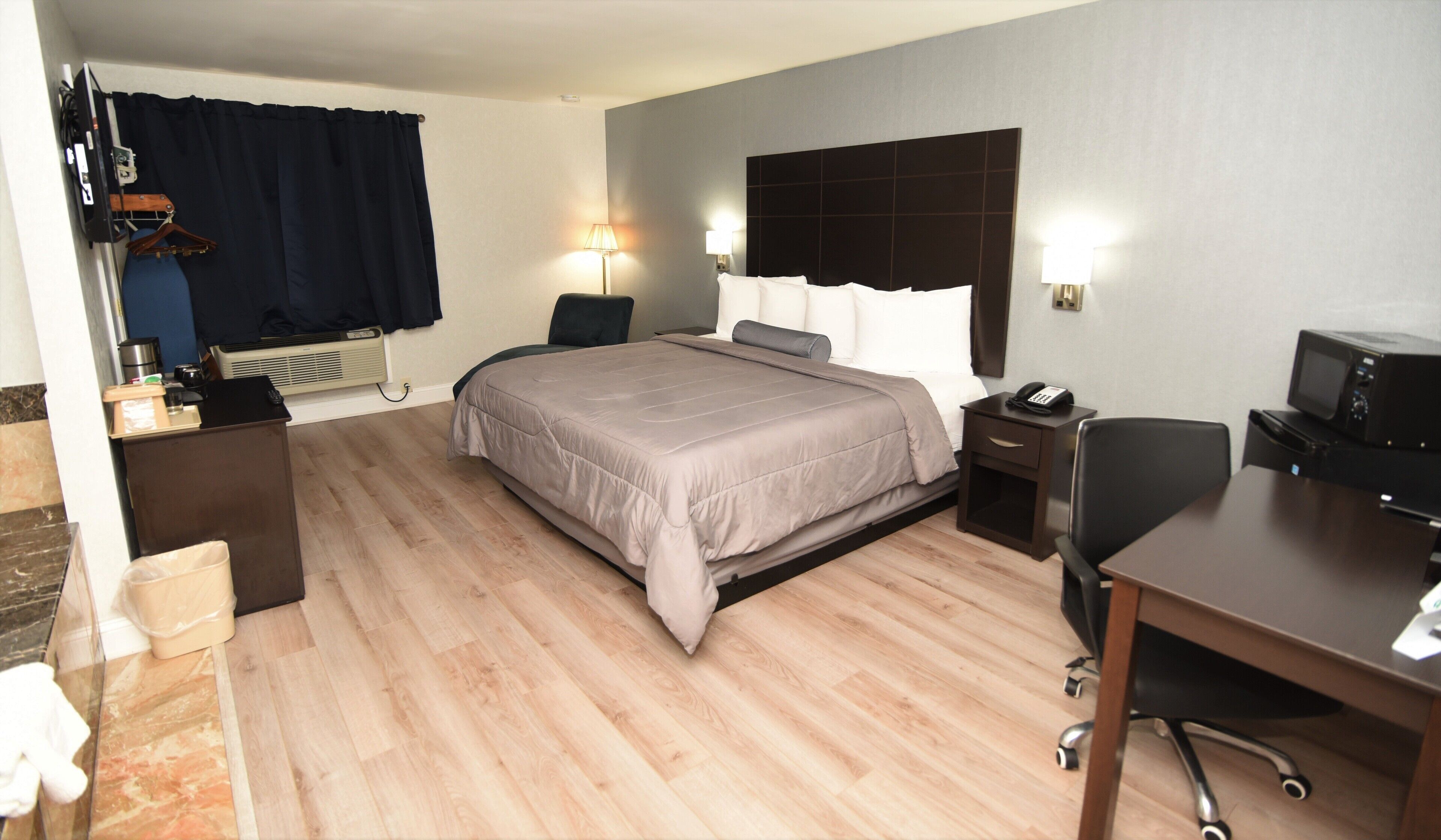 Habitación de hotel con cama, mesitas de noche, escritorio, silla, televisor y microondas.