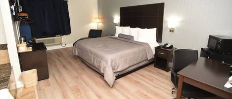 Habitación de hotel con cama, mesitas de noche, escritorio, silla, televisor y microondas.
