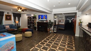 A lobby with a checkered floor, a fireplace, a television, a reception desk, and a bookshelf. - FairBridge Hotel Atlantic City (Absecon)