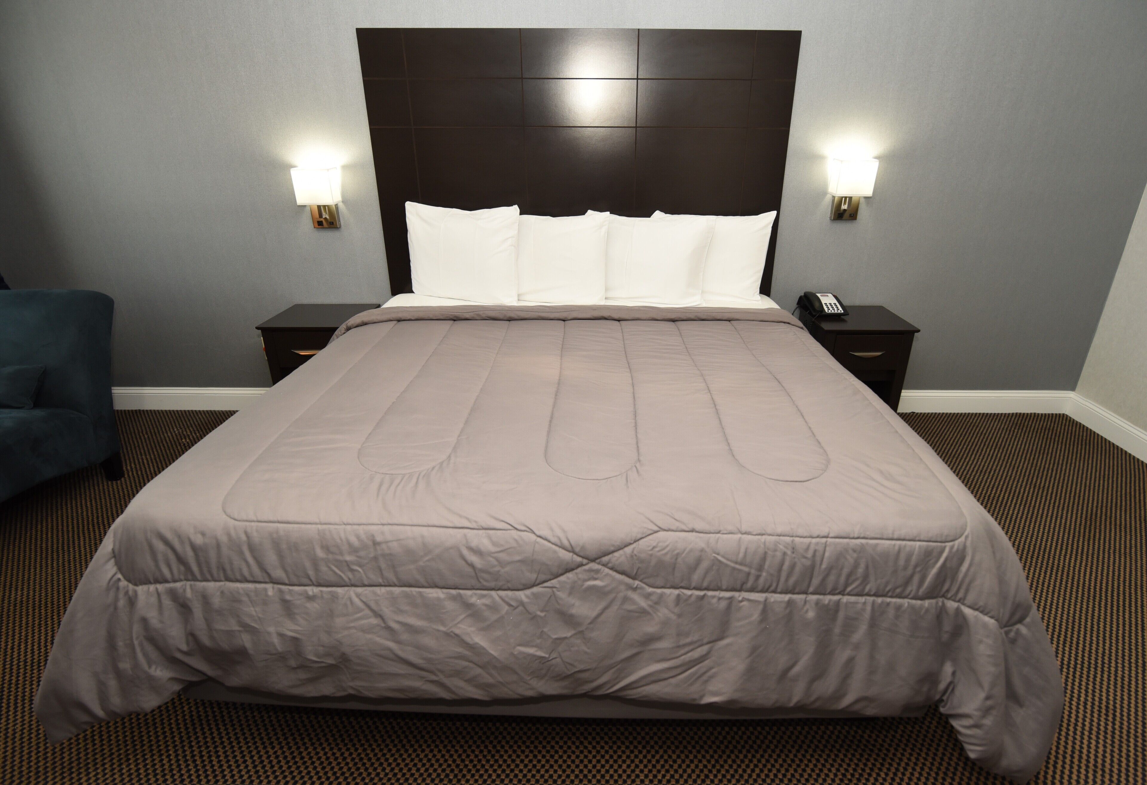 Een groot bed met hoofdeinde, twee nachtkastjes en twee wandlampen.