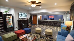 A lobby with a checkered floor, a television, a refrigerator, and a reception desk. - FairBridge Hotel Atlantic City (Absecon)