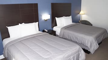 A hotel room with two beds, a nightstand, a lamp, and a chair.