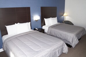 Ein Hotelzimmer mit zwei Betten, einem Nachttisch, einer Lampe und einem Sessel.