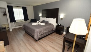Een hotelkamer met een bed, nachtkastjes, een bureau, een stoel, een lamp, een telefoon en een raam met gordijnen.