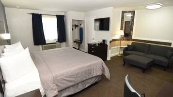 Una habitación de hotel con cama, sofá, televisor y espejo.