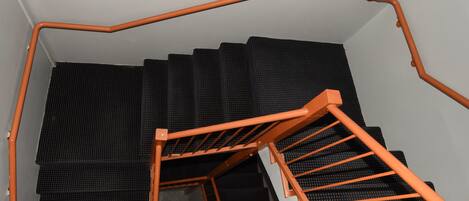 A staircase with orange metal railings and black textured walls.