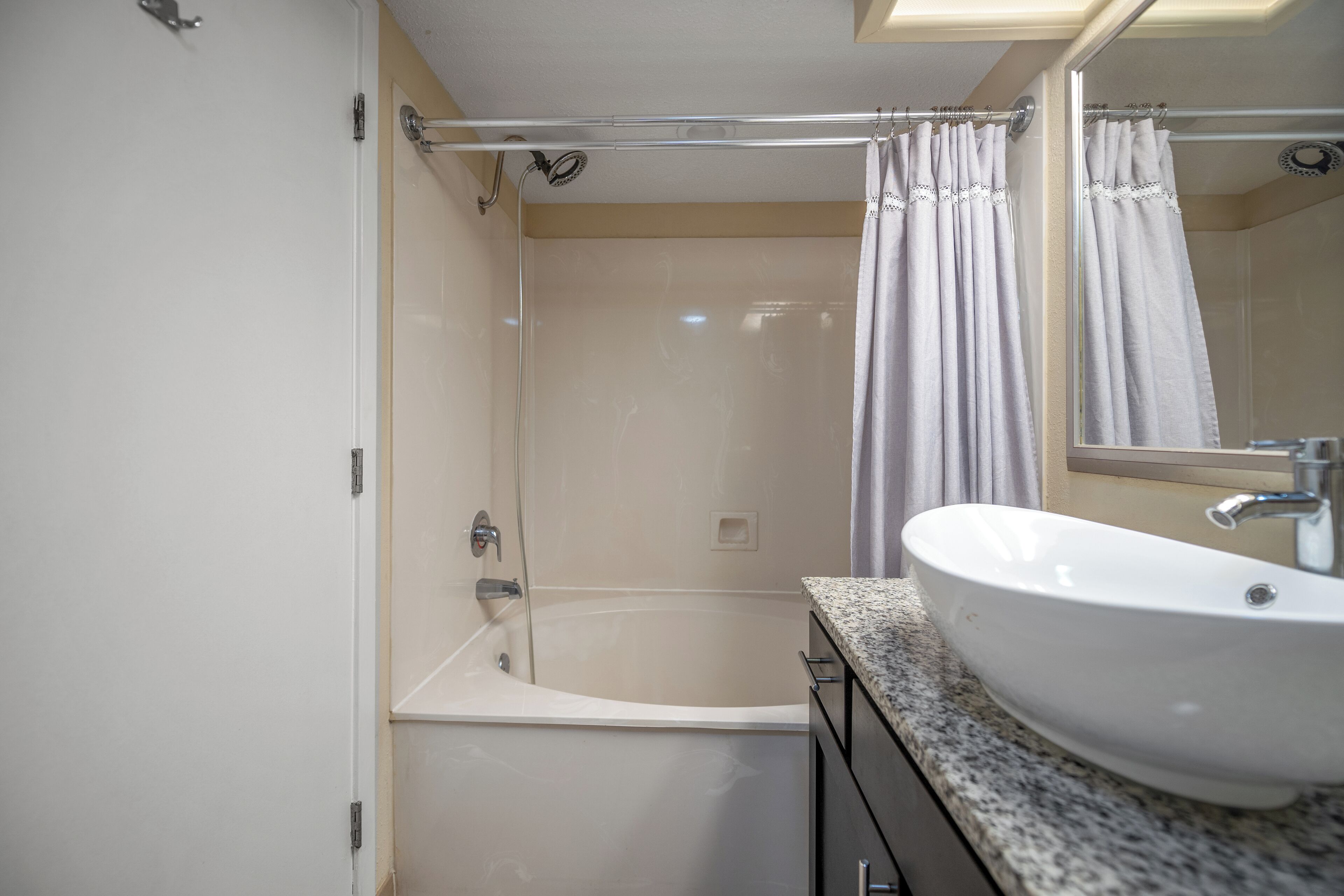 A bathroom with a bathtub, a sink, and a shower curtain.