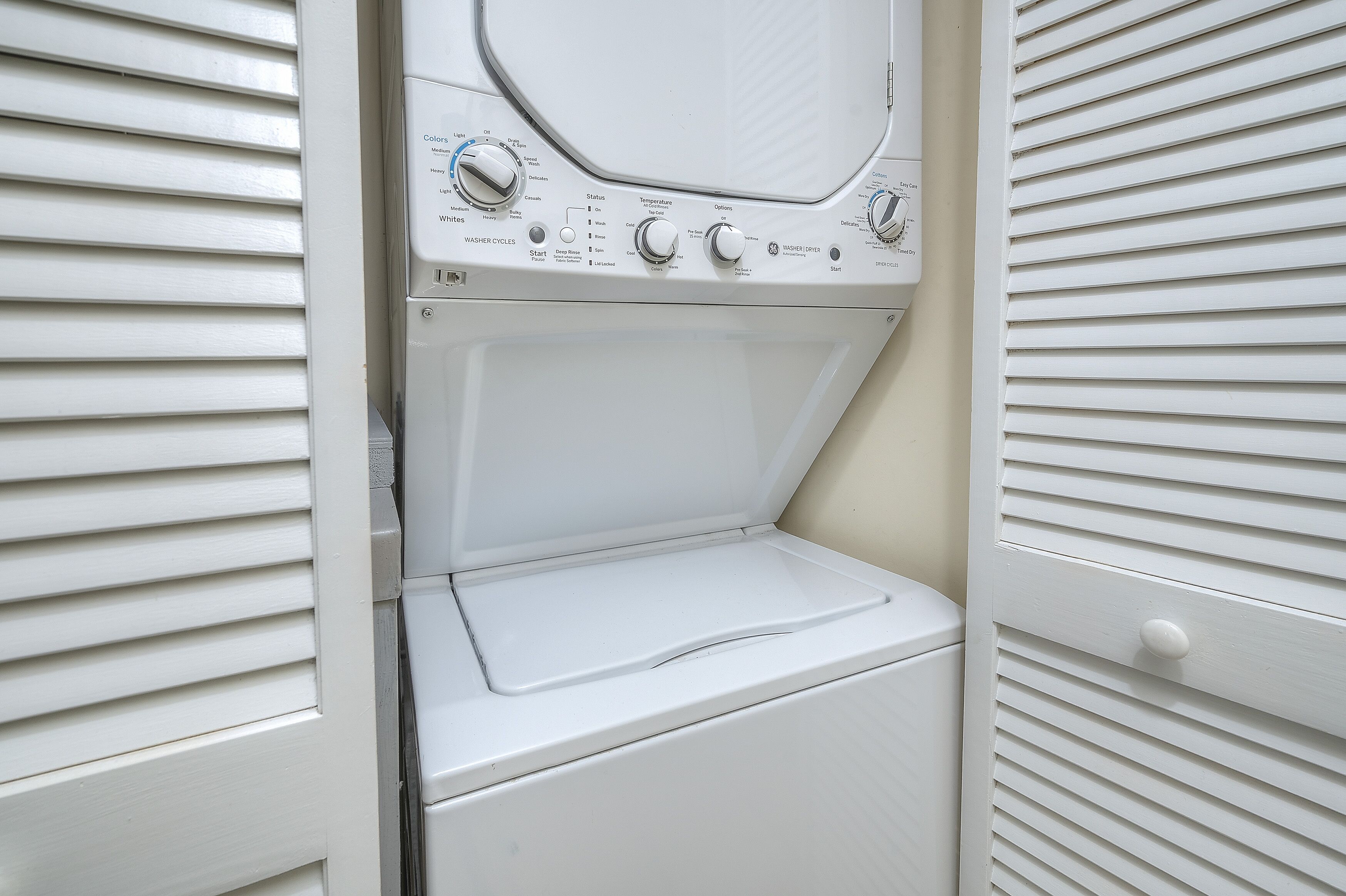 A white wall-mounted washer and dryer unit with control knobs and a start button.