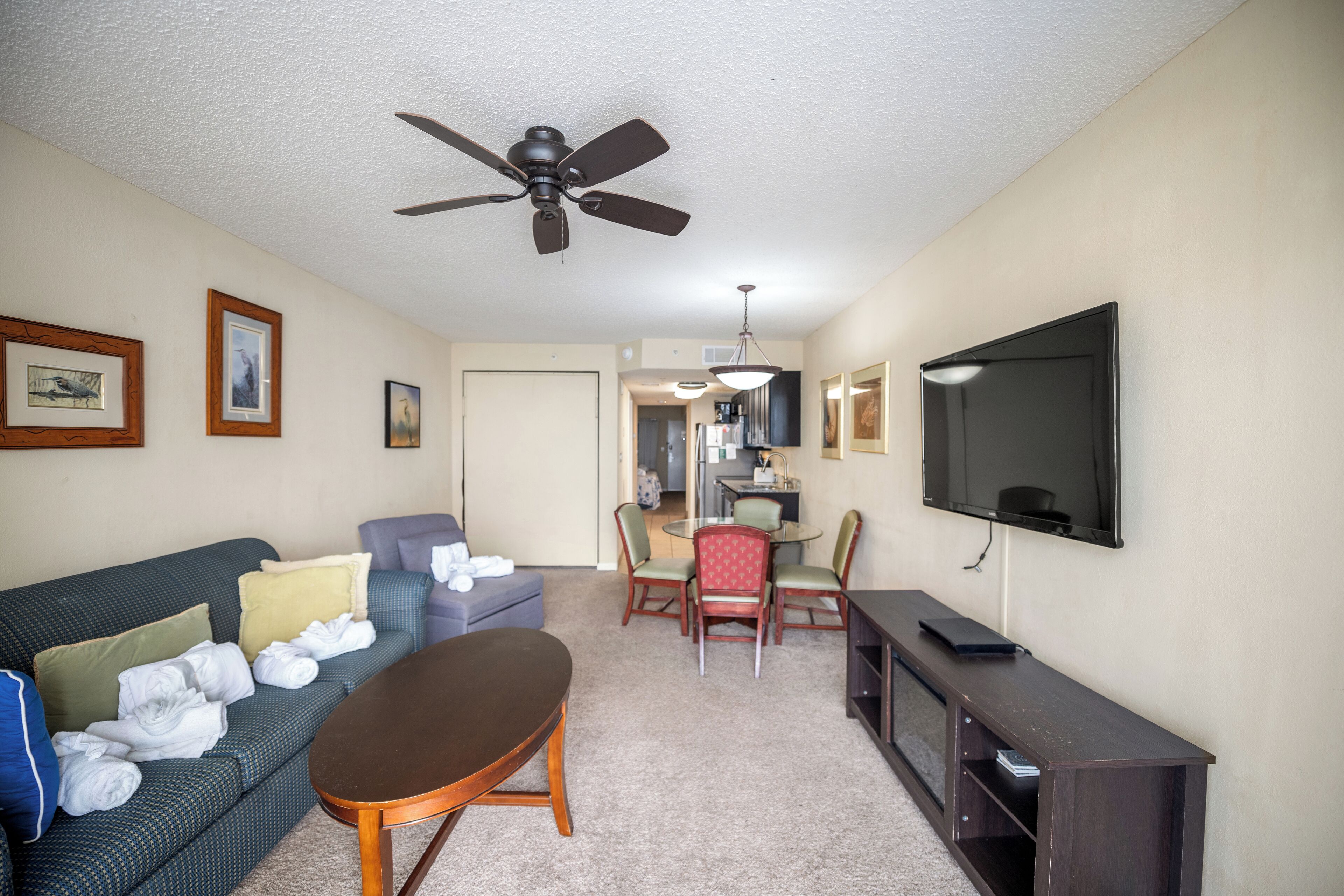 A living room with a sofa, a coffee table, a TV, and a ceiling fan.