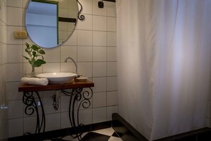 A bathroom with a white sink, a mirror, a potted plant, and a shower curtain. - Niños Hotel Fierro (Cusco)