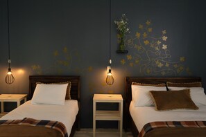 Two beds with white linens, a small bedside table, and a wall-mounted light fixture. - Niños Hotel Fierro (Cusco)