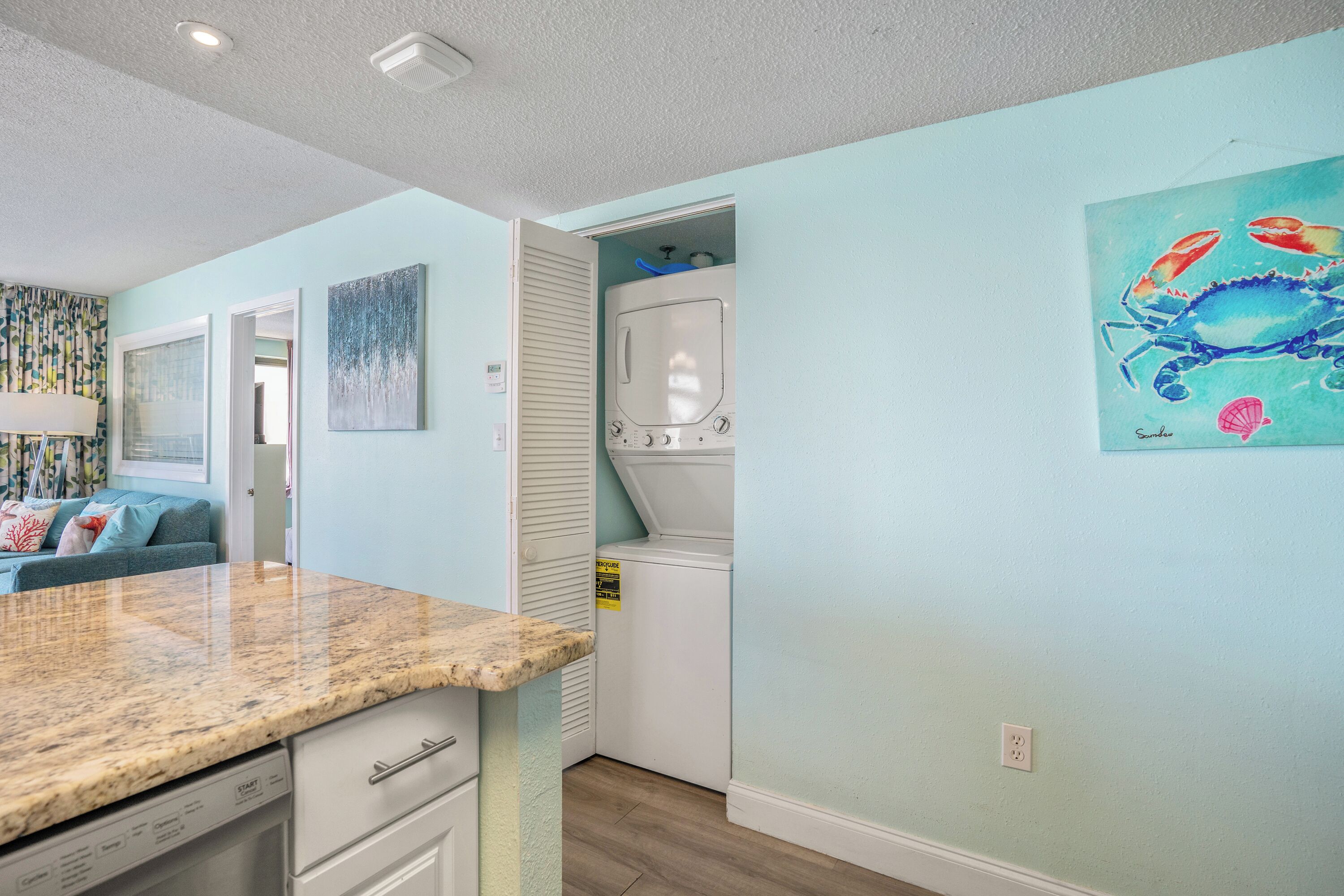 A compact kitchen with a granite countertop, a built-in oven, and a washing machine in the corner.