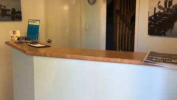 A reception desk with a wooden top and a white base, a clock on the wall, and a door leading to another room.