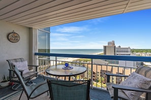 Enjoy the ocean view from this balcony with a round table and two cushioned chairs.
