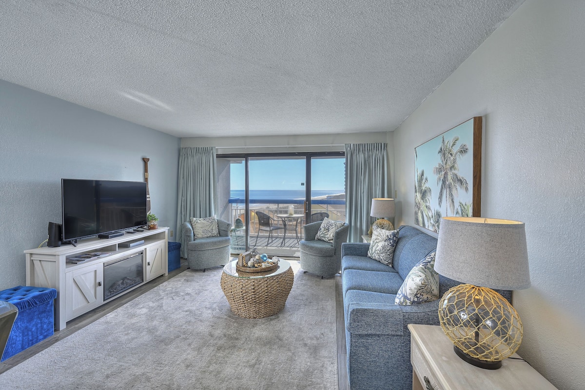 A living room with a flat-screen TV, a round coffee table, a sofa, and a lamp.