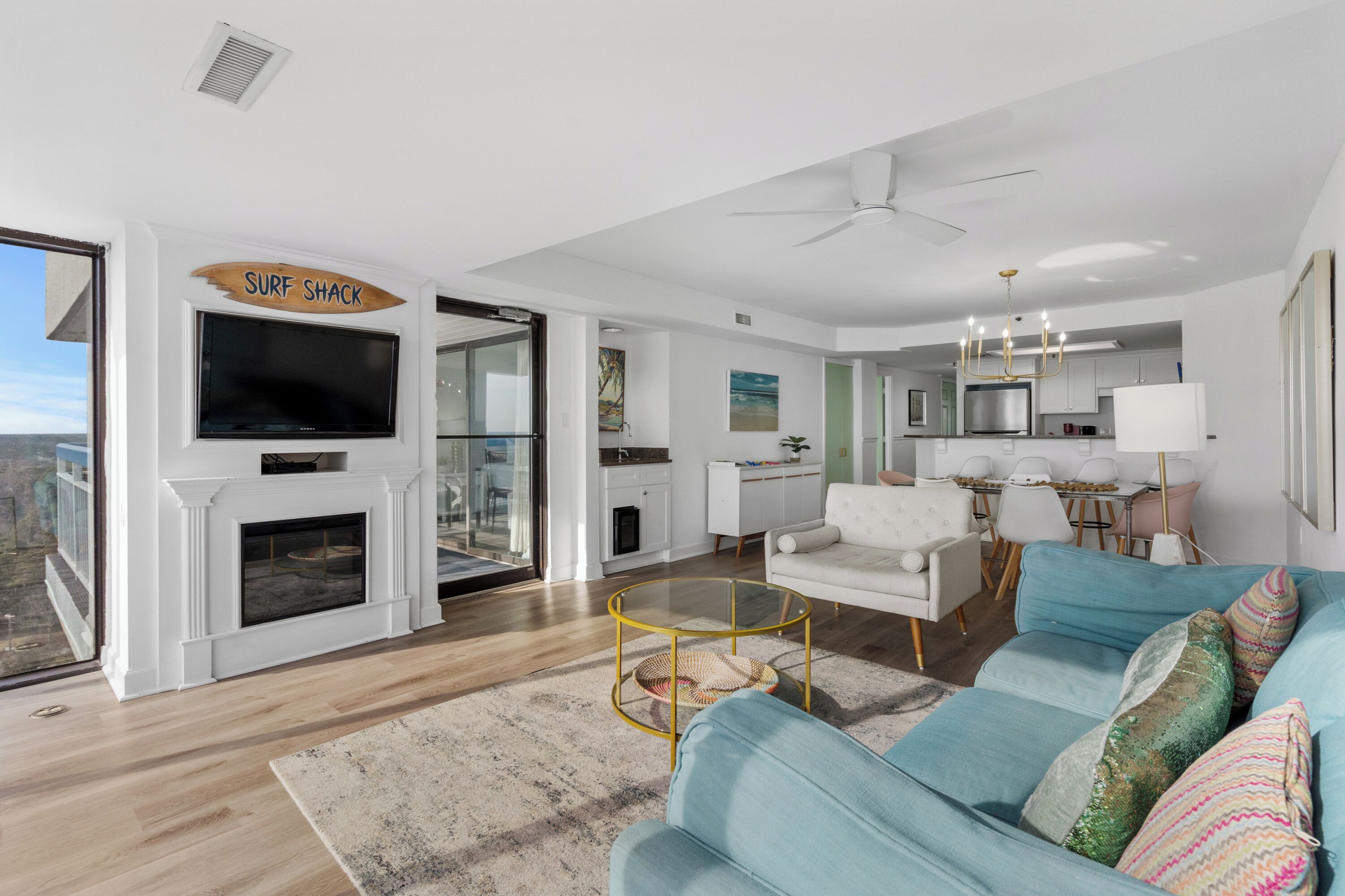 A modern living room with a fireplace, a television, a dining area, and a kitchen.