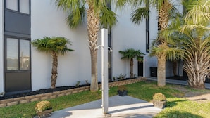A modern building with a concrete pathway, palm trees, and a small garden area. - Holiday Towers by Elliott Beach Rentals (Myrtle Beach)