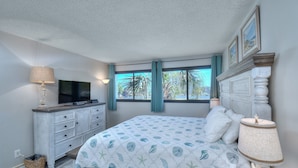 A bedroom with a bed, a TV, a dresser, and a window with curtains. - Holiday Towers by Elliott Beach Rentals (Myrtle Beach)