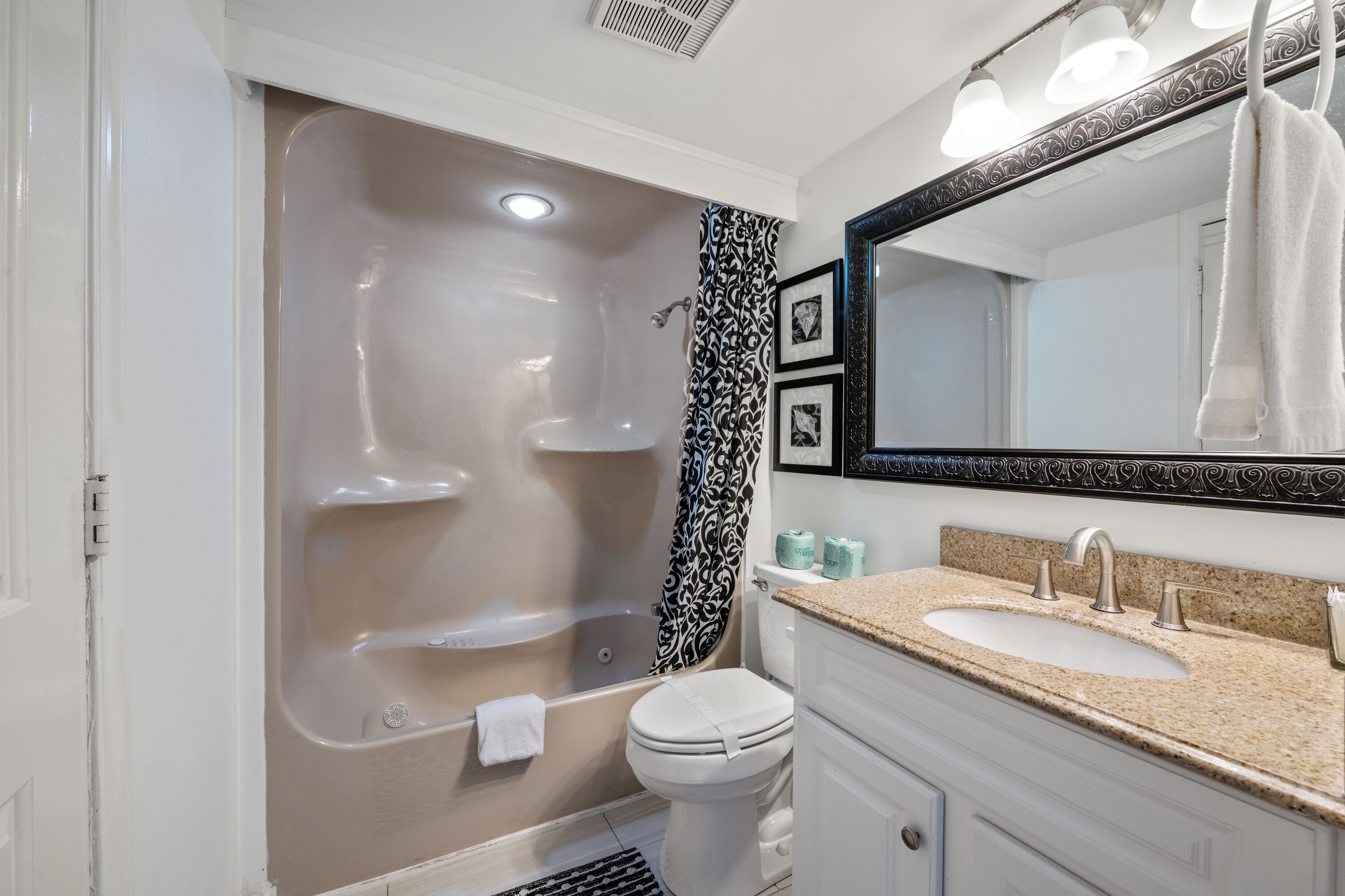 Une salle de bain équipée d’une baignoire, de toilettes, d’un lavabo et d’un grand miroir.