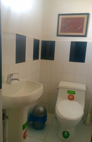 A bathroom with a sink, toilet, and trash bin. - Casa Ceasars  Historic Quito (Quito)