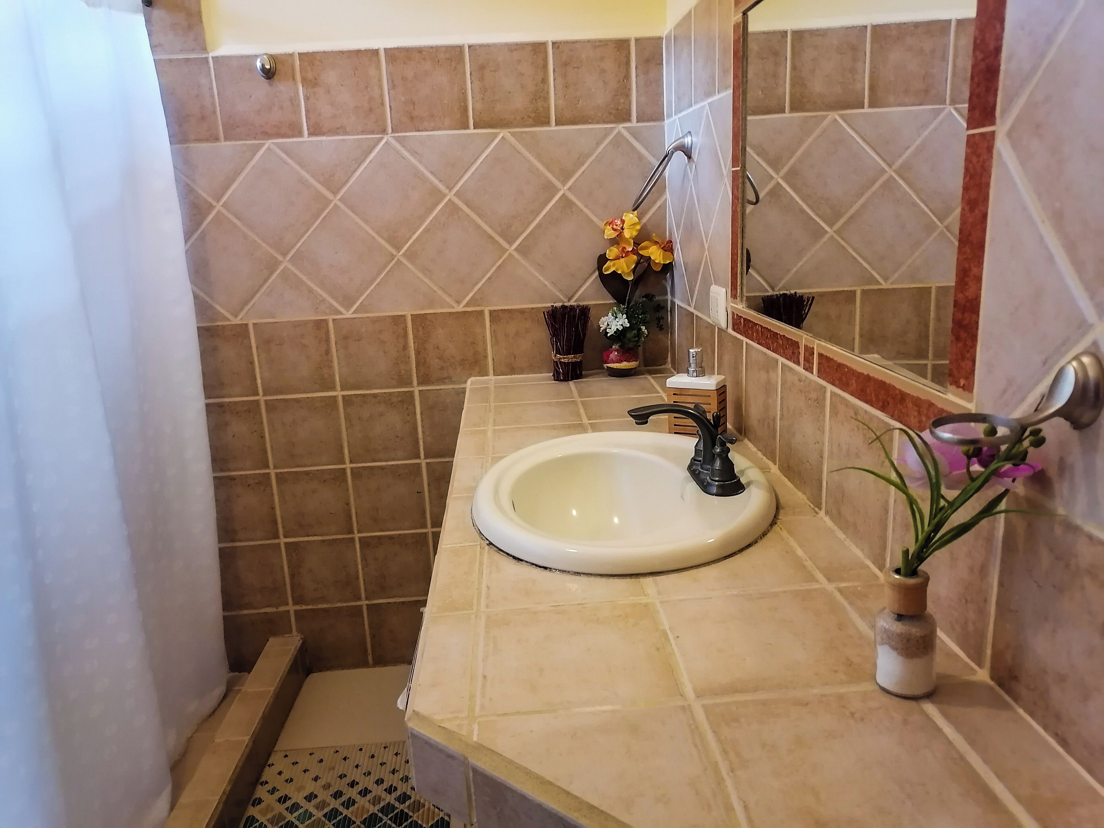 Un baño con lavamanos, espejo y paredes de azulejos.