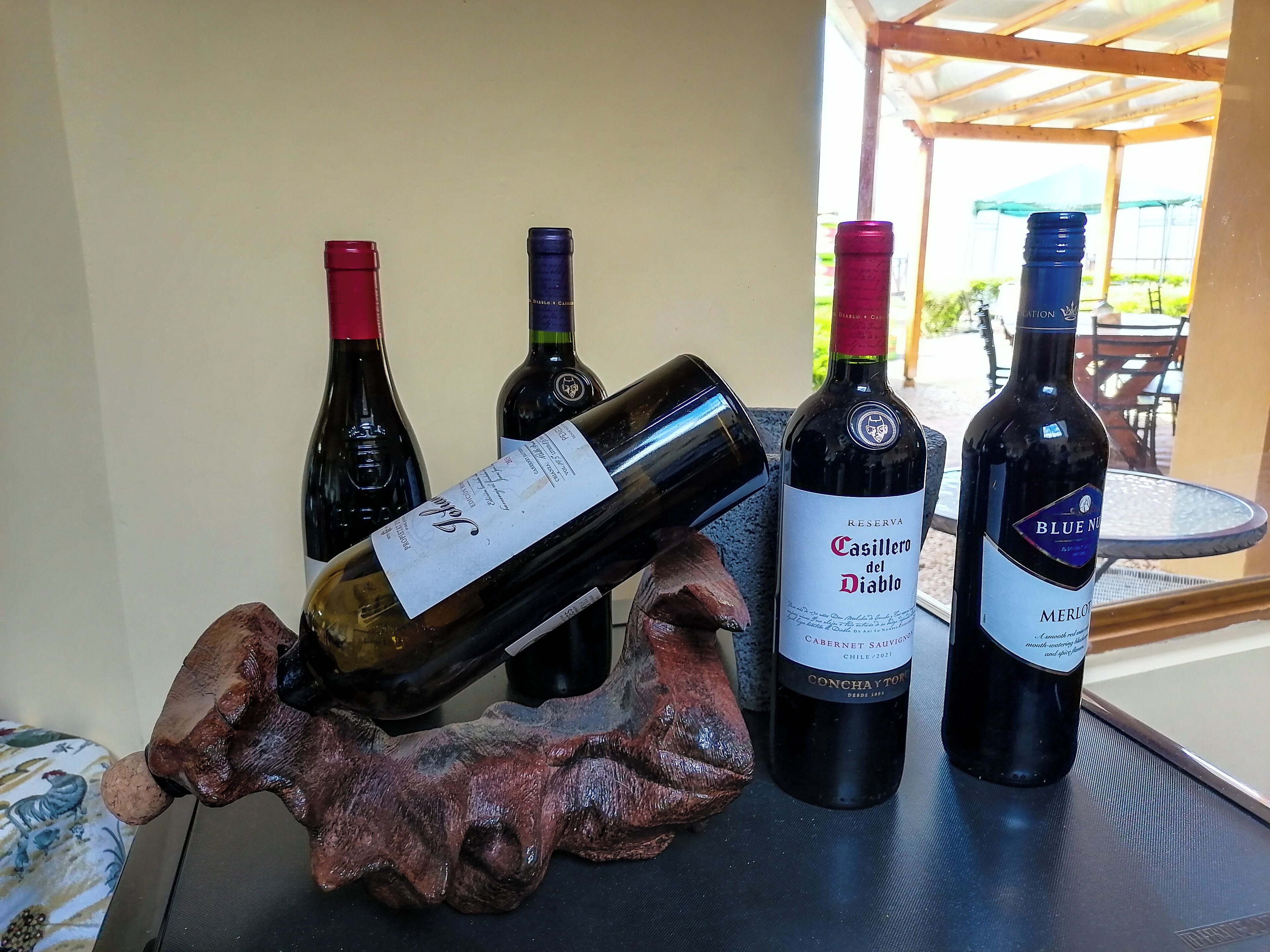 Una mesa con cuatro botellas de vino y una escultura de madera.