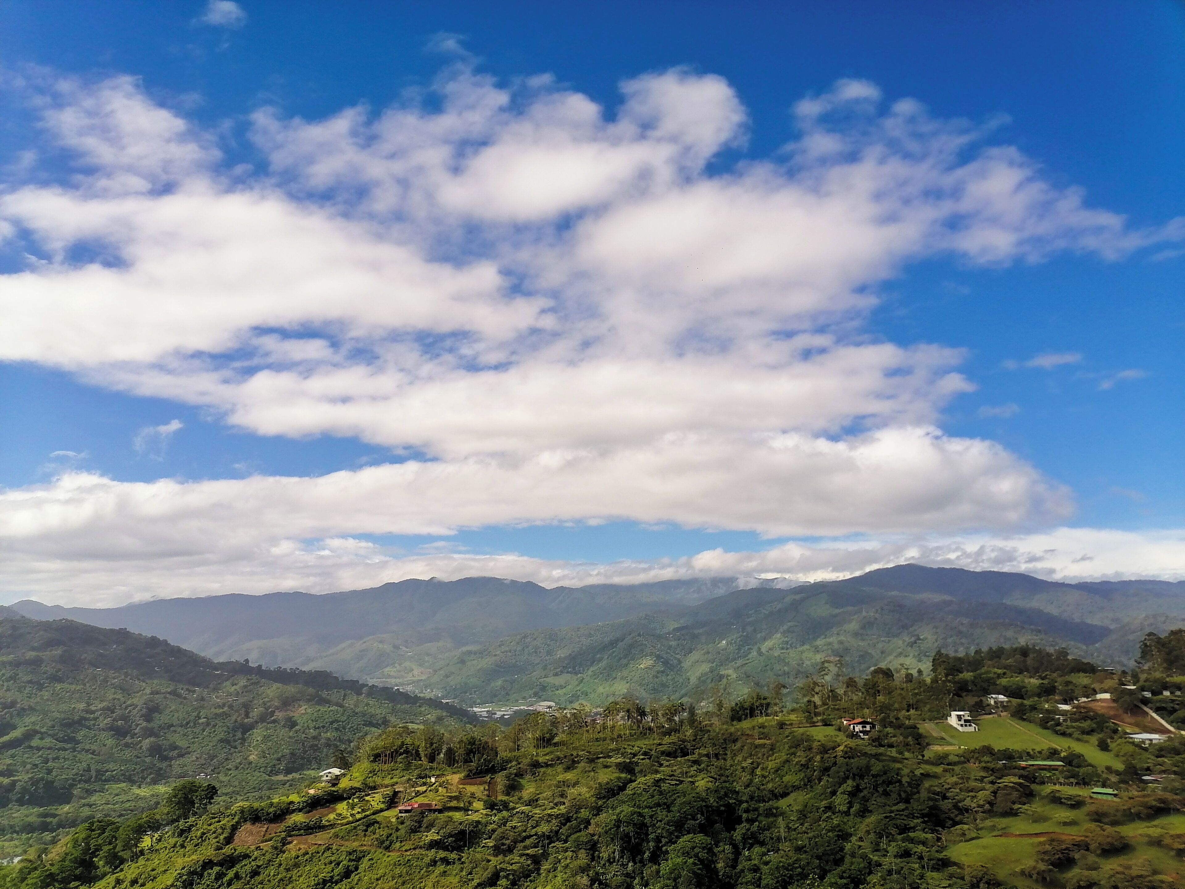 A panoramic view of a mountainous landscape with scattered houses and lush greenery.